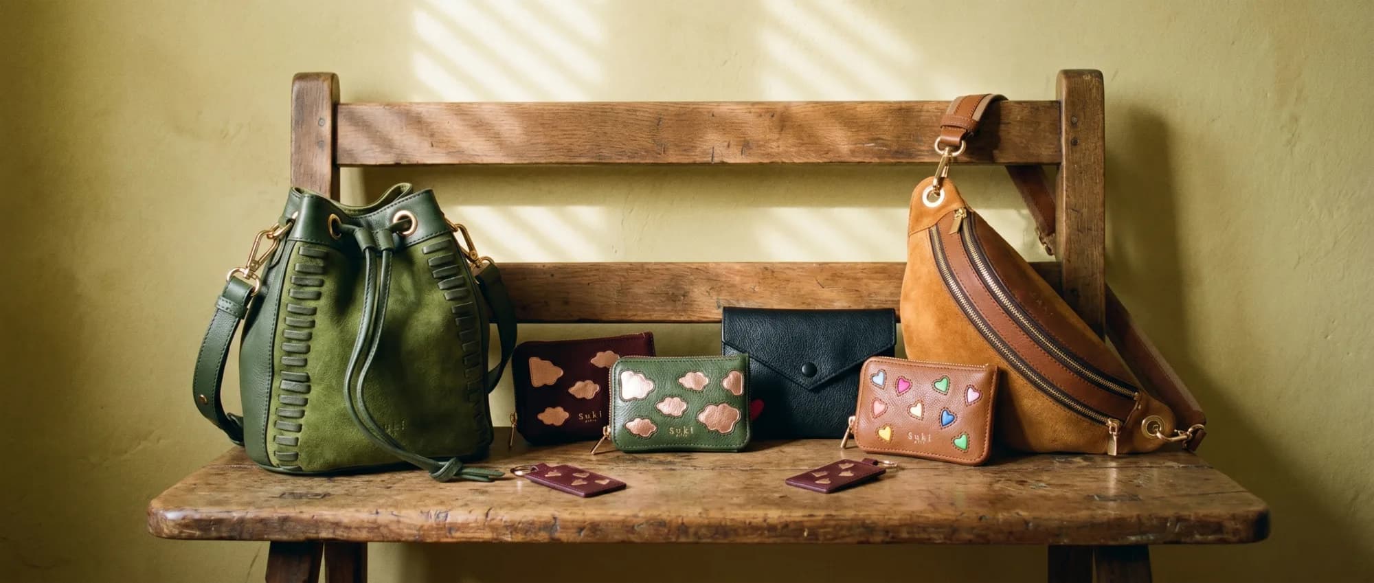 Ensemble de petits accessoires en cuir Suki Paris posés sur un banc