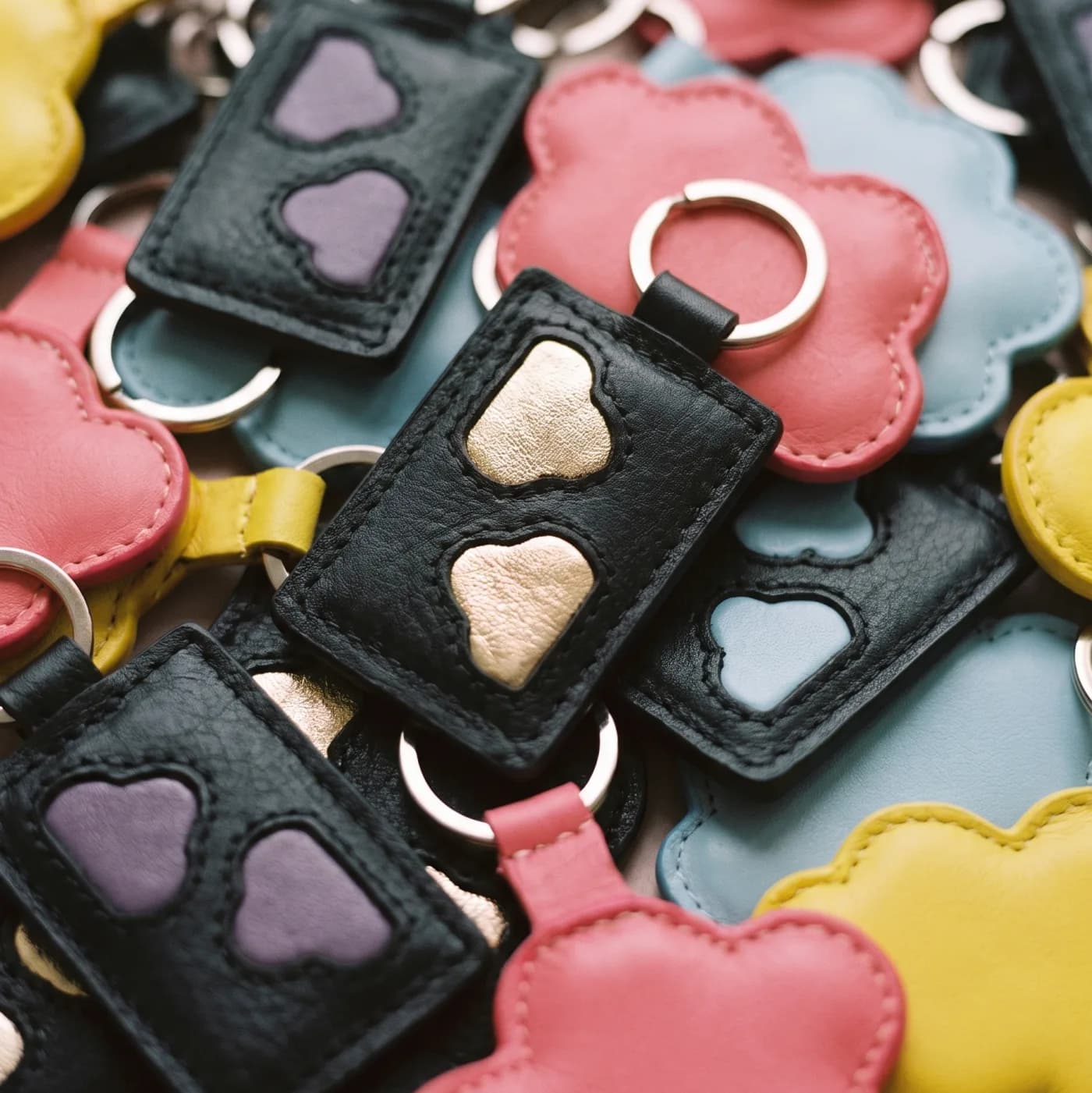 Colourful leather keyrings stacked — inlaid hearts and rings, Suki Paris atelier